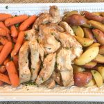 Carrots, chicken, and potatoes on a white serving platter