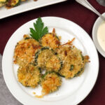 Individual zucchini parmesan chips on a white plate.