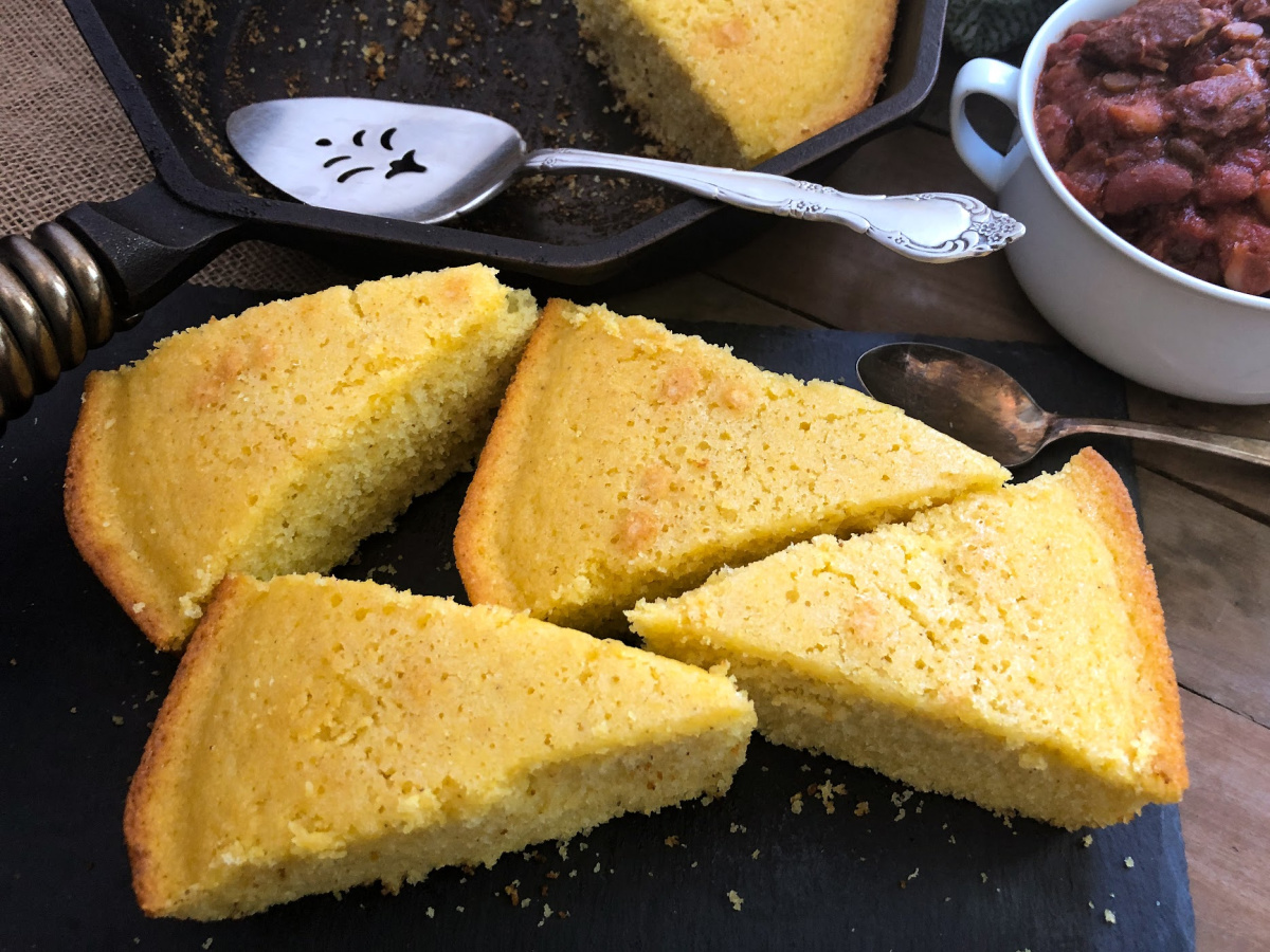 Triangle slices of sweet cornbread on a black platter.