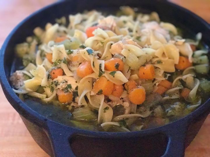 Blue Dutch oven of chicken noodle soup.