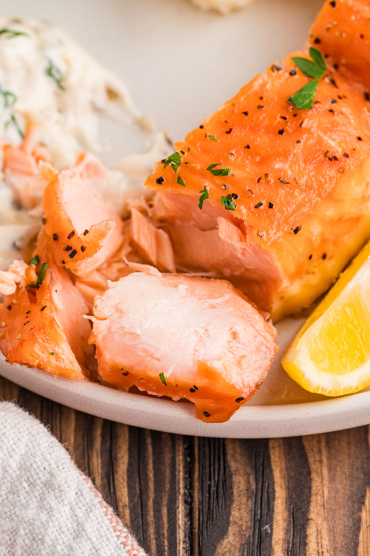 Pieces of hot smoked salmon flaked off on a plate.