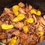 Cooked and Shredded Dutch Oven Mississippi Roast with lots of pepperoncinis.