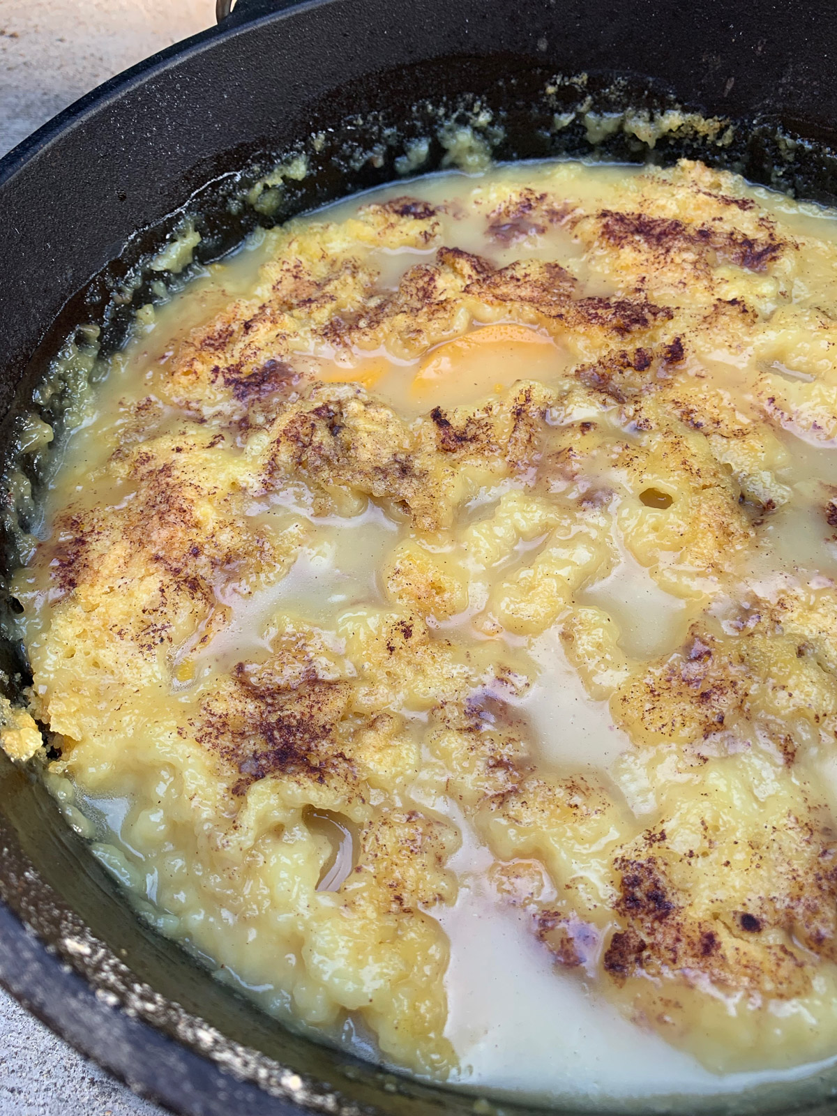A cast iron dutch oven filled with peach dump cake.