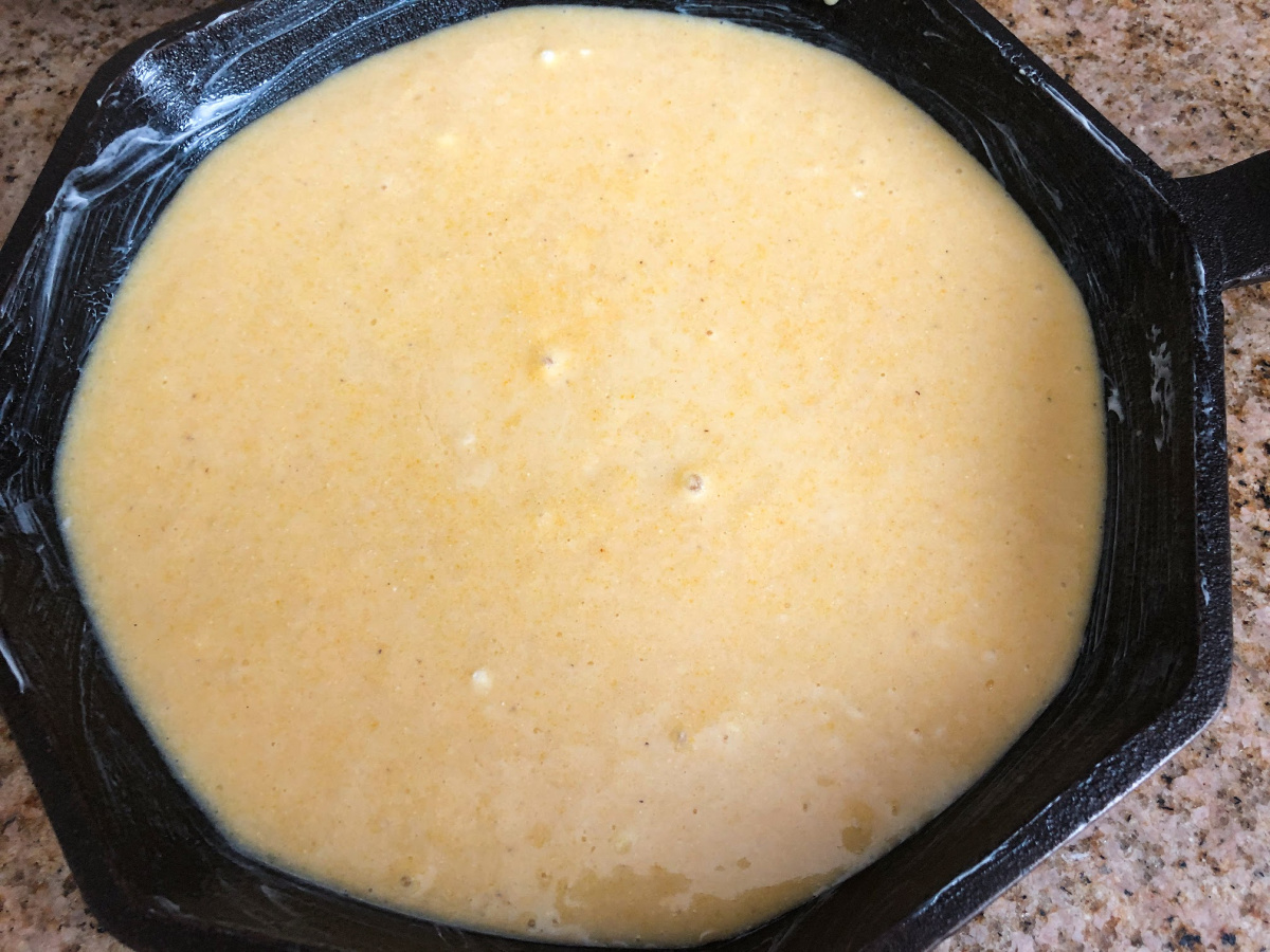 The sweet cornbread batter has been poured the prepared cast iron skillet. 