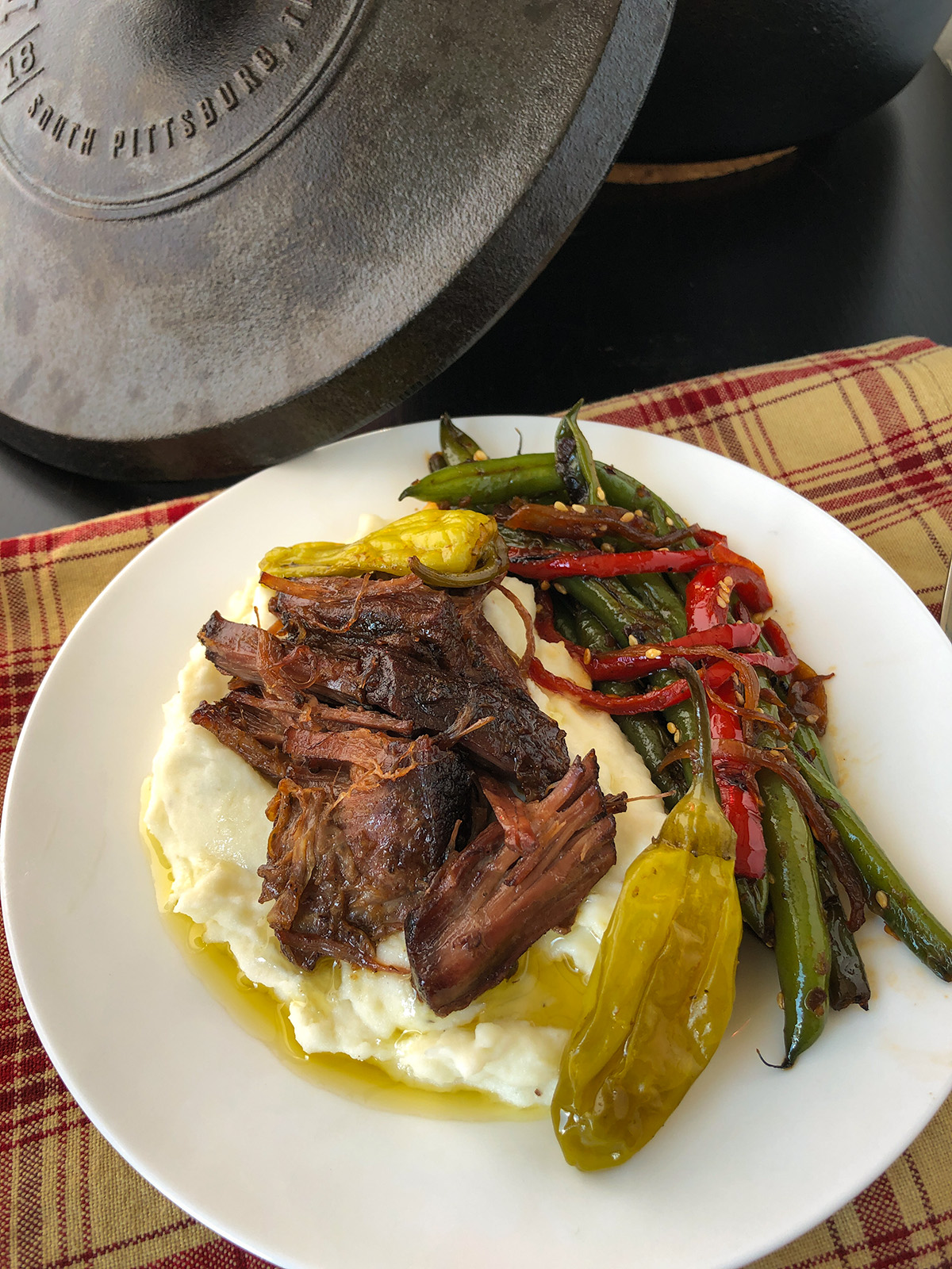 Dutch oven Mississippi pot roast over some mashed potatoes on a plate.