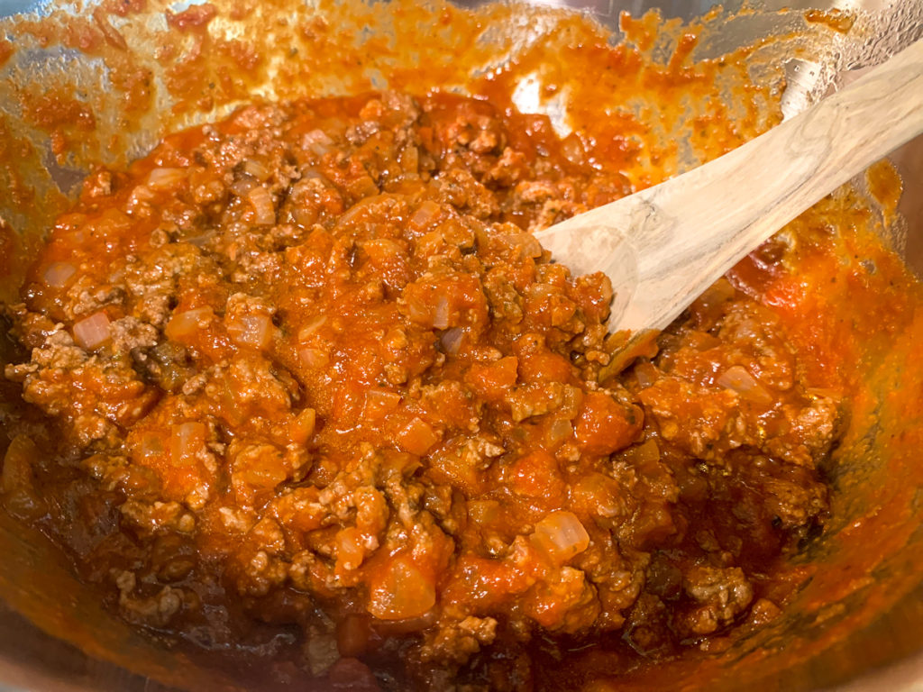 Pasta sauce has been added and mixed into the seasoned ground beef. 