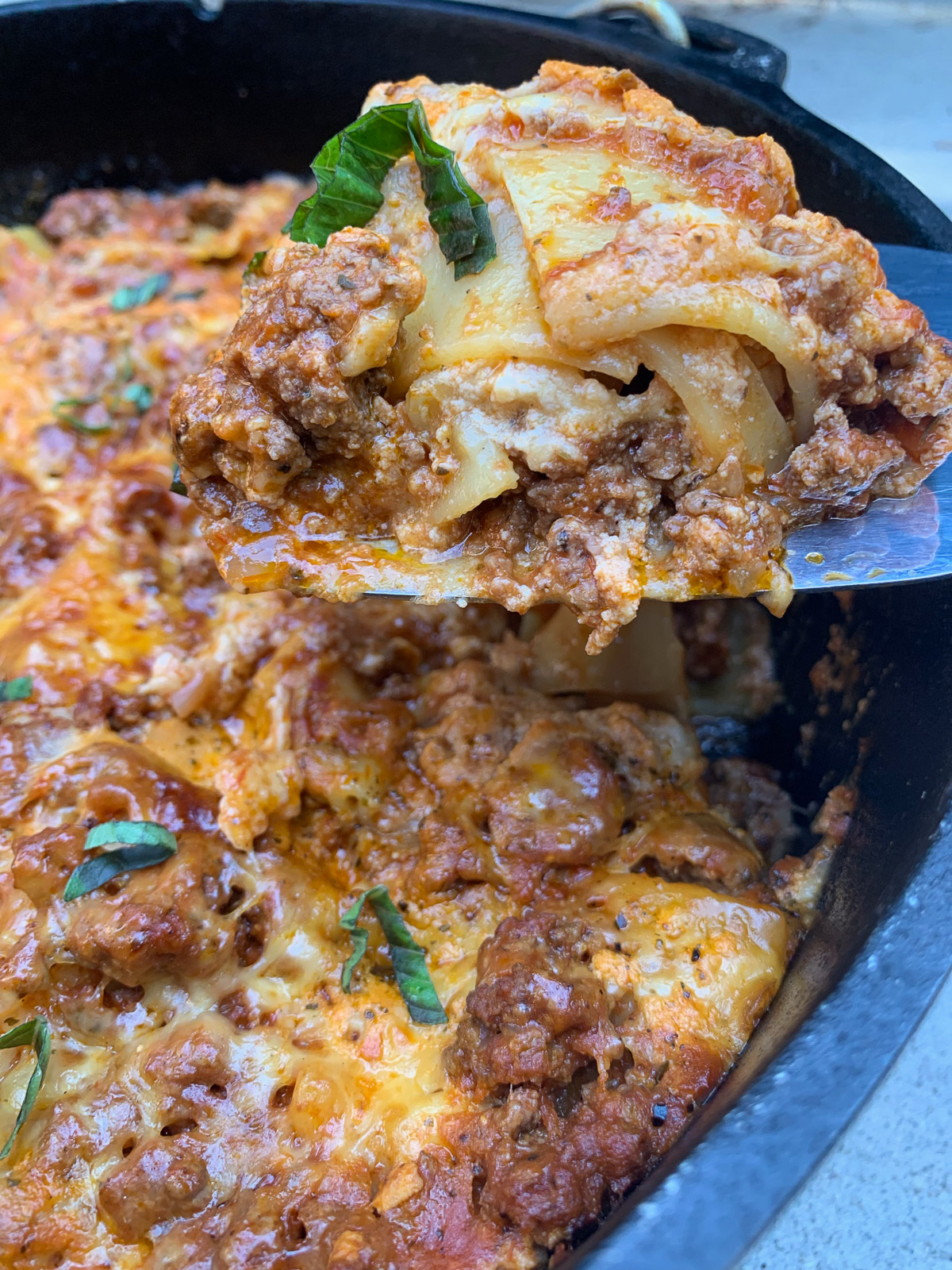 A spatula lifting up a piece of Dutch oven lasagna.