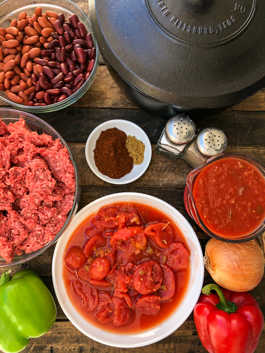 Raw and measured out ingredients for Awesome Chili: the Dutch oven, kidney beans, ground beef, spices, salsa, tomatoes, and bell peppers. 