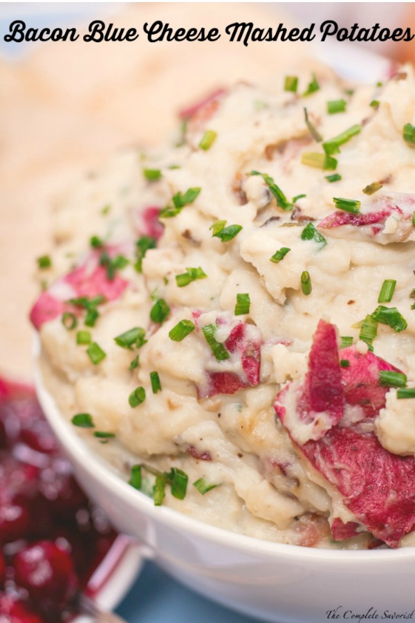 Brimming bowl of red potatoes mashed with bacon and blue cheese, garnished with chives. 