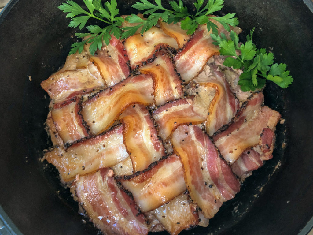 Cooked Dutch Oven Peppered Bacon Meatloaf garnished with fresh parsley. 