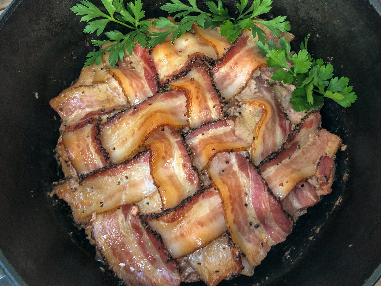 Cooked Dutch oven peppered bacon meatloaf garnished with fresh parsley