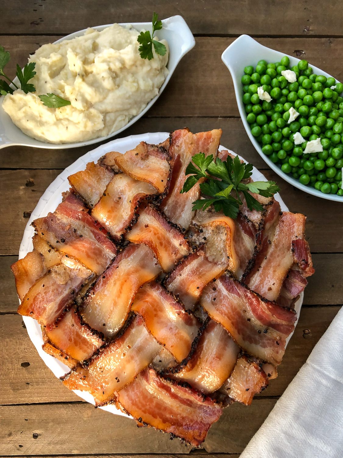 Peppered bacon meatloaf garnished with fresh parsley served with mashed potatoes and green beans. 