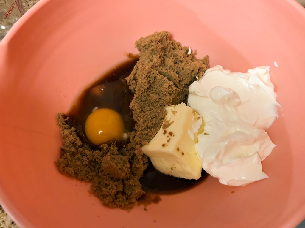 Vanilla extract, softened salted butter, sour cream, brown sugar and egg in a pink bowl. 