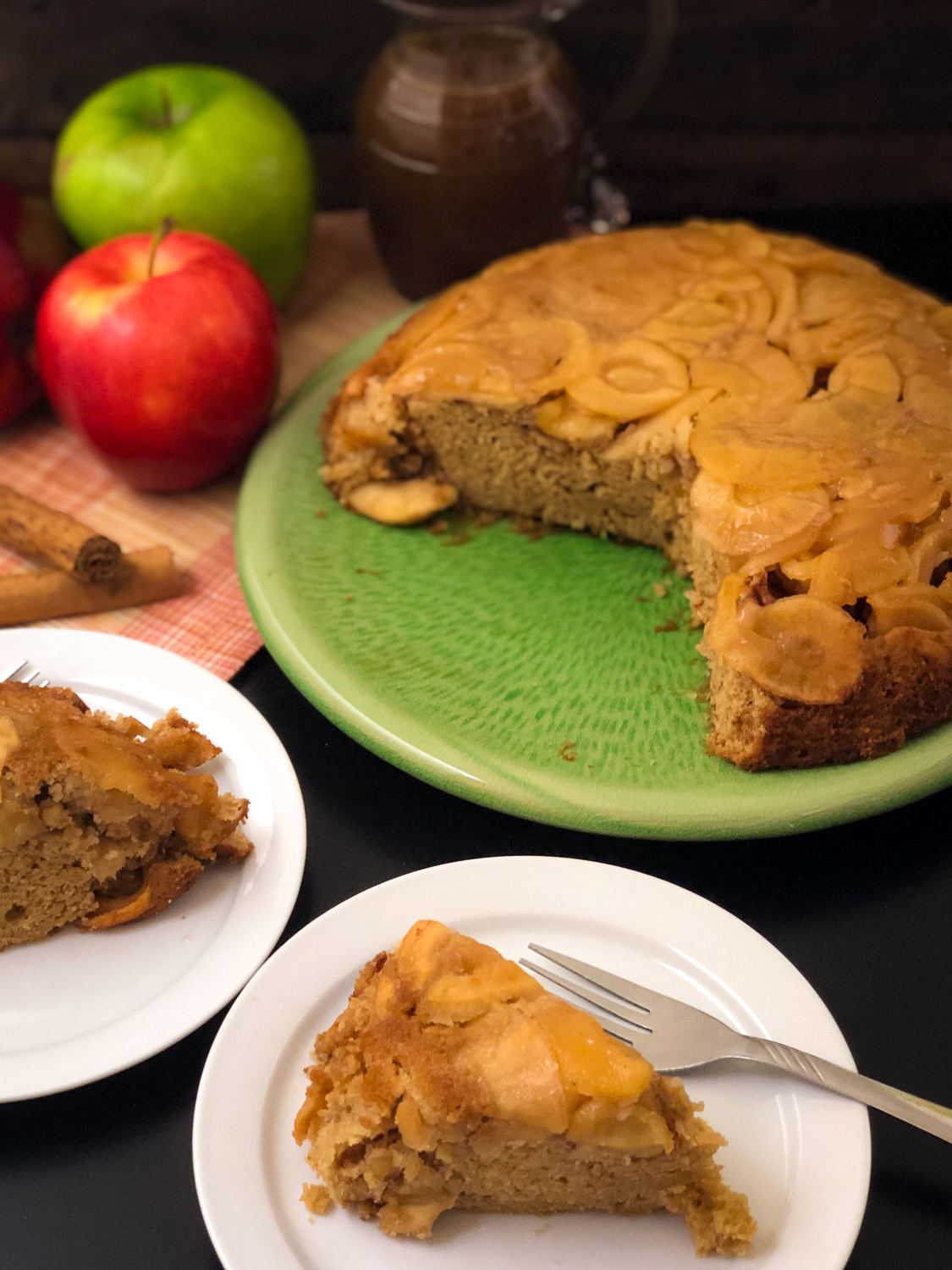 Two slices of apple cake with the remaining on a platter in the background. 