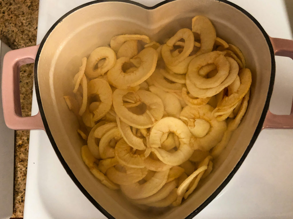 Dehydrated apples being rehydrated in an enameled cast iron dutch oven on the stove top. 