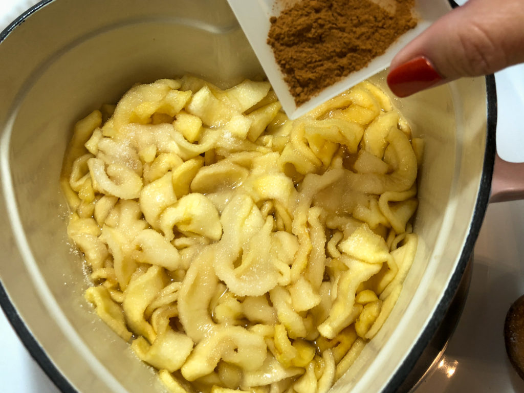 Sugar has been spread over apples and the cinnamon is being added. 