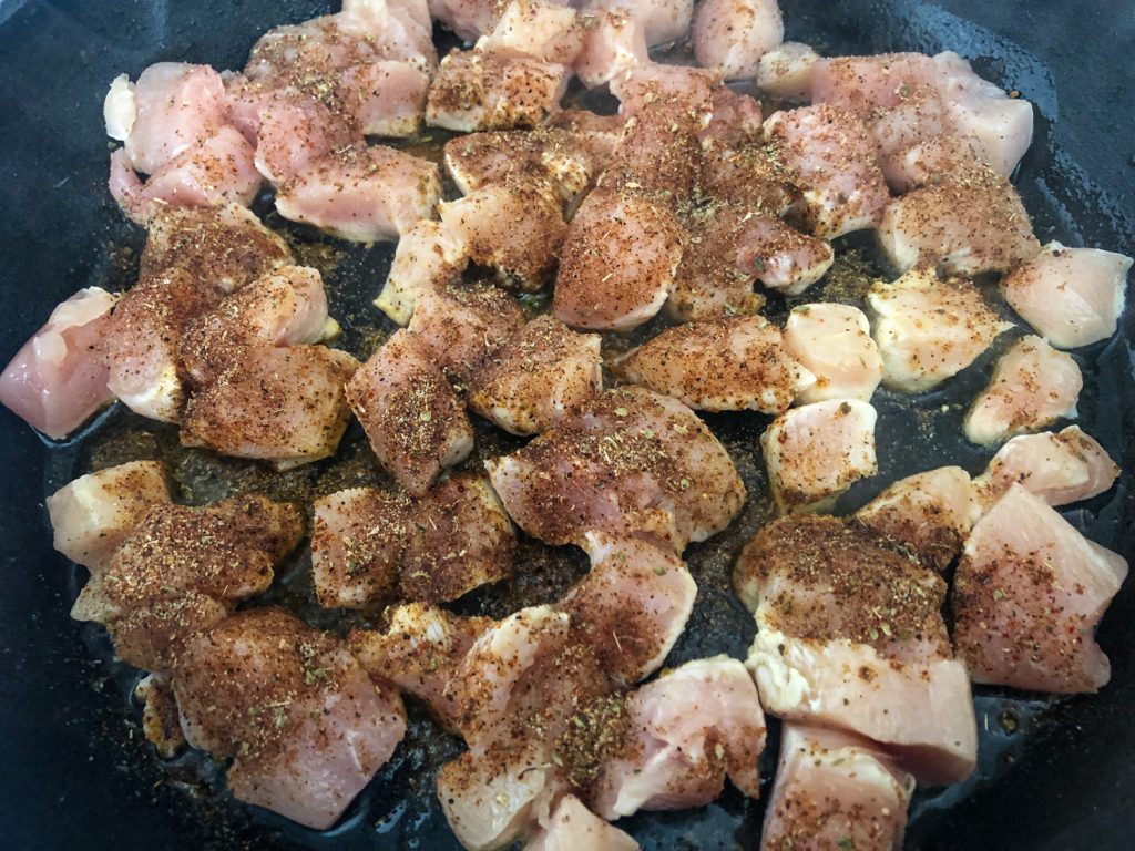 Chicken searing in a cast iron skillet that has been seasoned with a Mexican spice blend. 