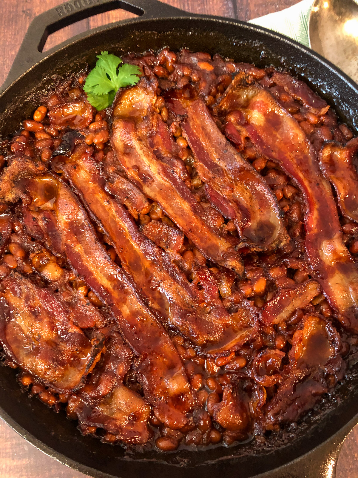 Cast iron skillet of bacon topped baked beans.