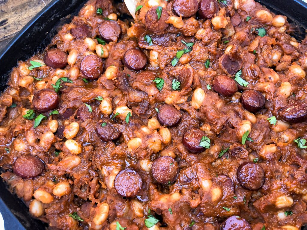 Cooked and ready to serve skillet beanie weenies garnished with fresh parsley. 