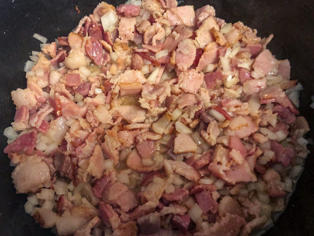 Chopped bacon and onions cooking in a Dutch Oven