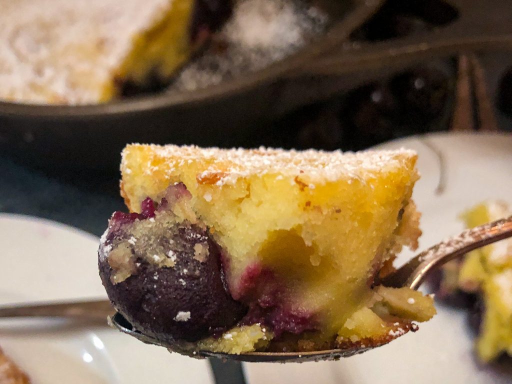 A bite of cherry clafoutis on a spoon to show the texture of the dessert. 