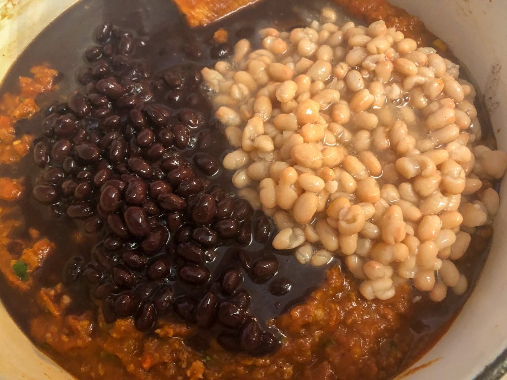 Cans of undrained black and white beans have been added to the chili. 