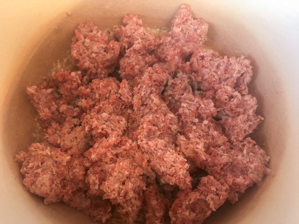 Ground sausage has been crumbled into the Dutch oven to brown. 