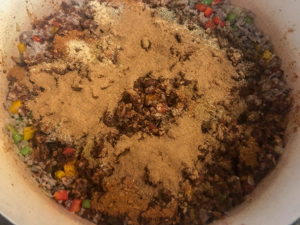 Chili mix packet, salt, pepper, cumin, garlic, and pumpkin pie spice to the cooked sausage and vegetables.