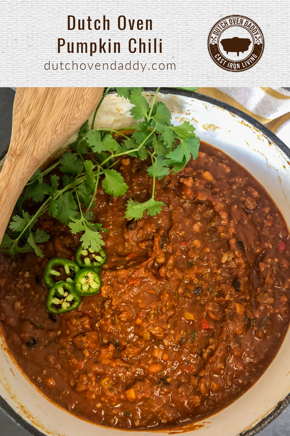 Dutch Oven Pumpkin Chili garnished with fresh cilantro and a wooden spoon atop. 