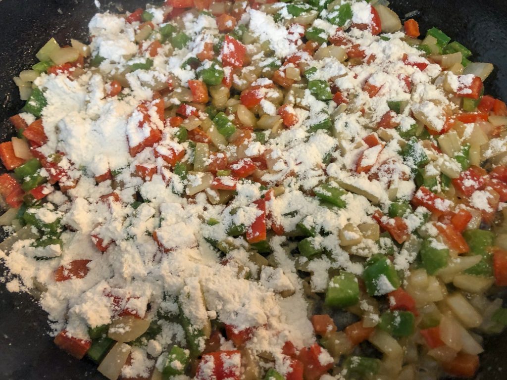 Flour has been sprinkled over the sautéed onions and pepper to make the roux.