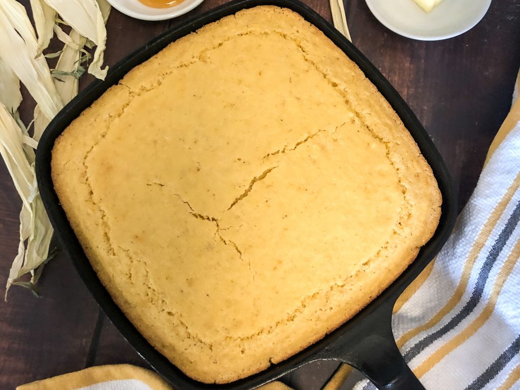 Baked and slightly cooked, the Skillet Creamed Corn Cornbread is ready to be sliced and served. 