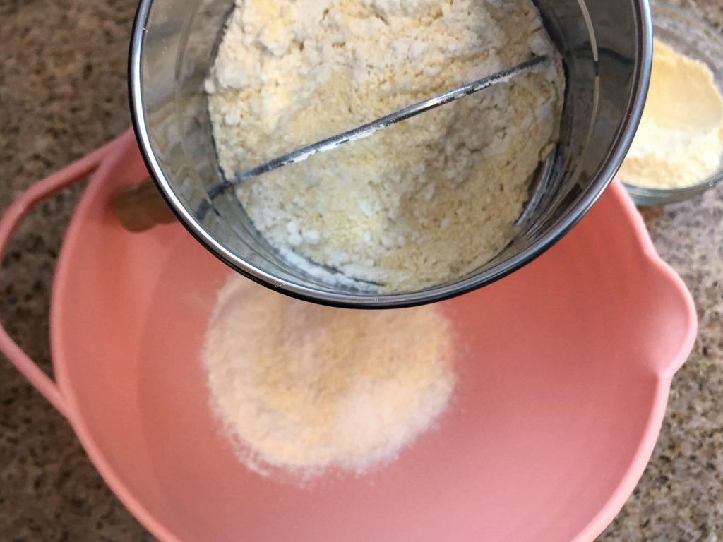 The dry ingredients in the sifter and some in a pink bowl after sifting. 
