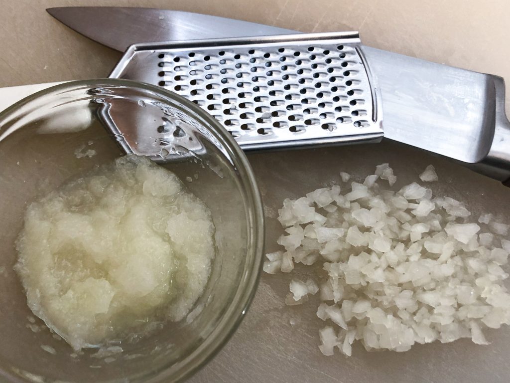Image showing both grated onion and finely diced onion, with the grater and knife in the background. 