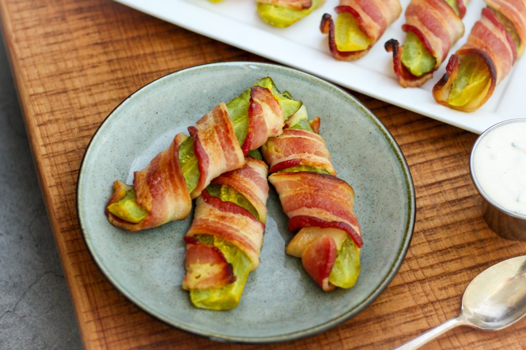 A plate of pickles wrapped in bacon. 