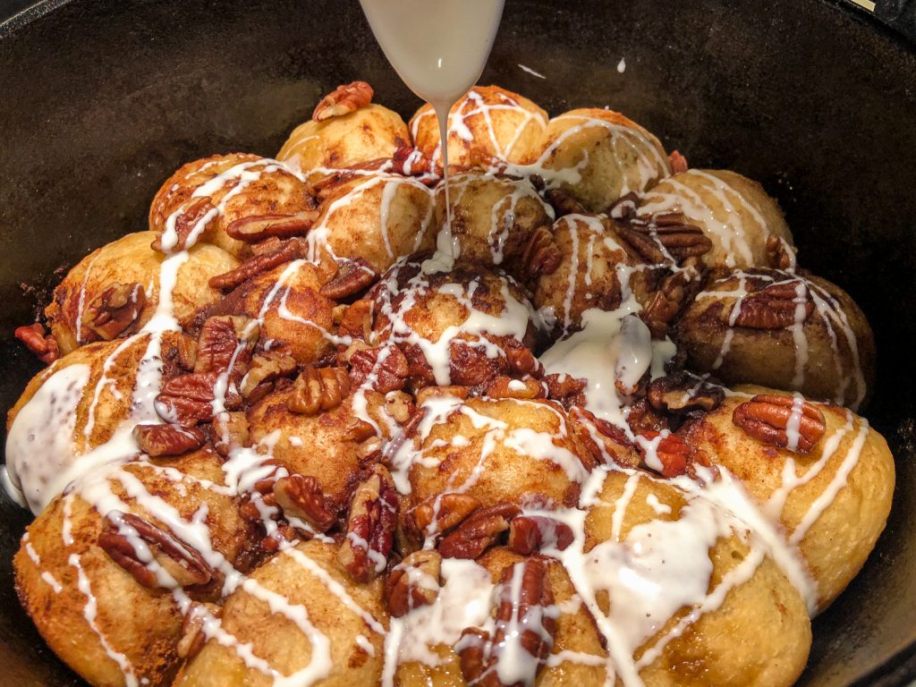 Prepared cream cheese frosting thinned with cream being drizzled over the hot baked sweet bread. 