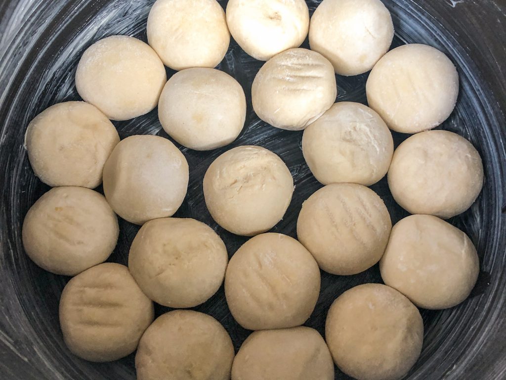 Frozen dough balls arranged in the coated pot to rise.