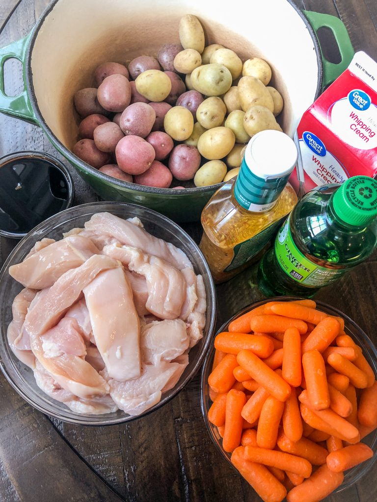 Ingredients needed to Dutch Oven Italian Chicken in Gravy: baby carrots, chicken breast in strips, ginger ale, Italian salad dressed, heavy cream, soy sauce, and both gold and red baby potatoes.