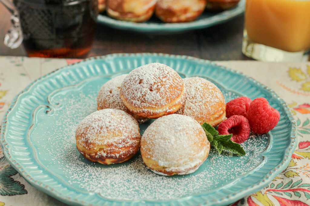 Plated Danish Aebleskiver dusted with powdered sugar.