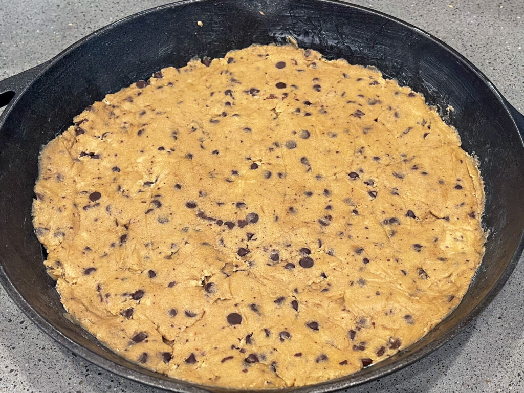 Nestle cookie dough in bare metal cast iron skillet.