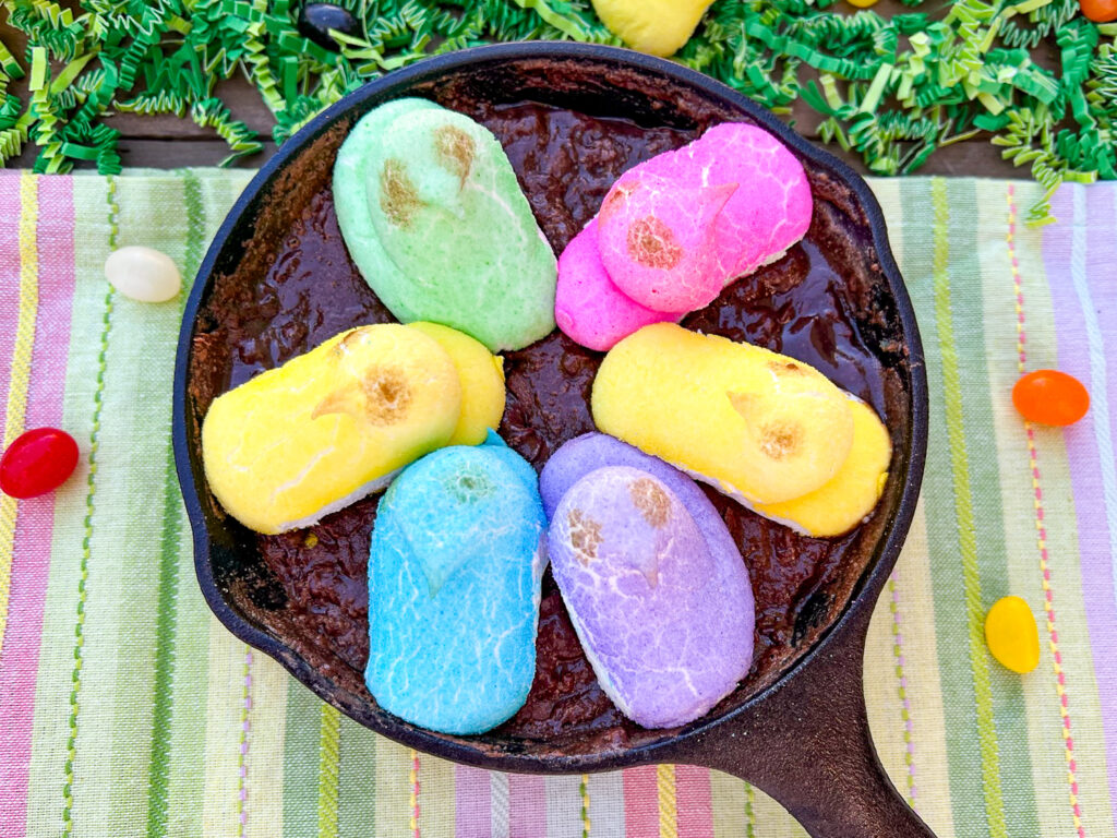 A cast iron skillet with chocolate peanut butter dip and toasted Peeps.