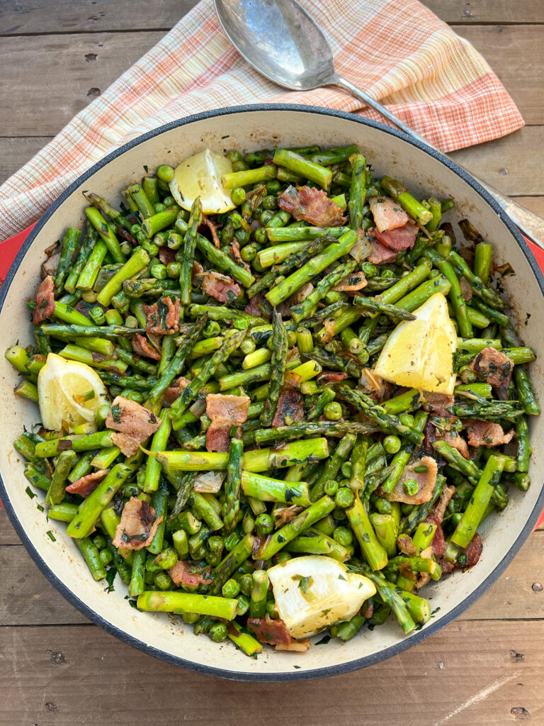 Finished dish of Dutch Oven Asparagus and Peas with bacon, leeks, fresh herbs, and lemon.