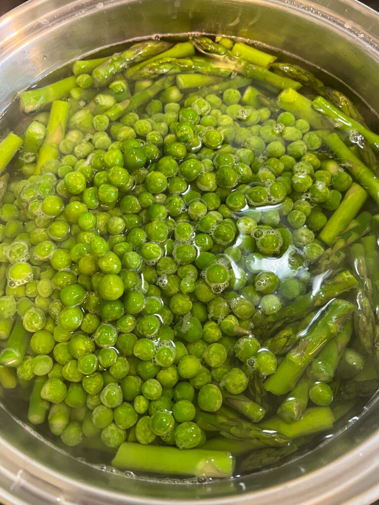 Asparagus and peas blanching in boiling salted water.