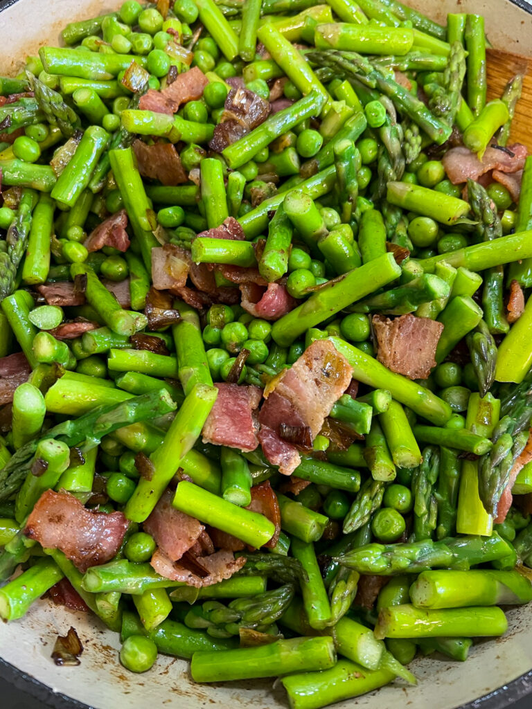Peas, bacon, leeks, and asparagus stirred together in the Dutch oven.