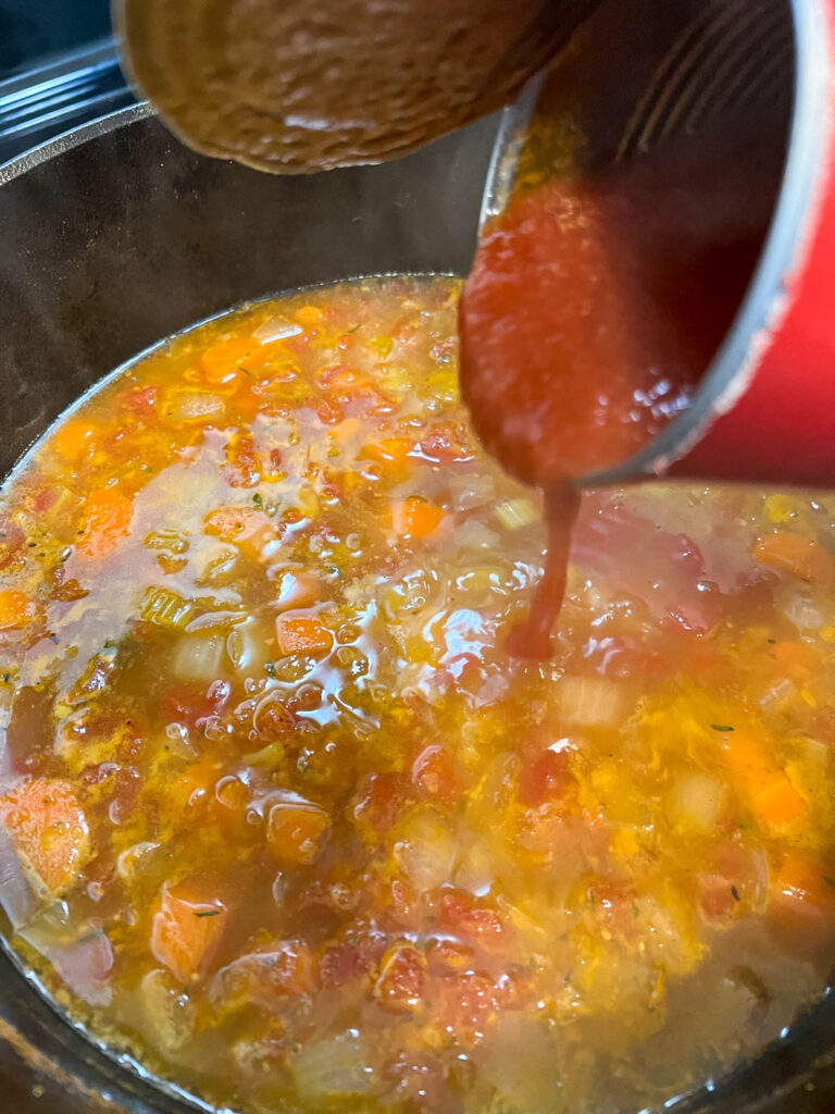 Tomato sauce being added to the soup.