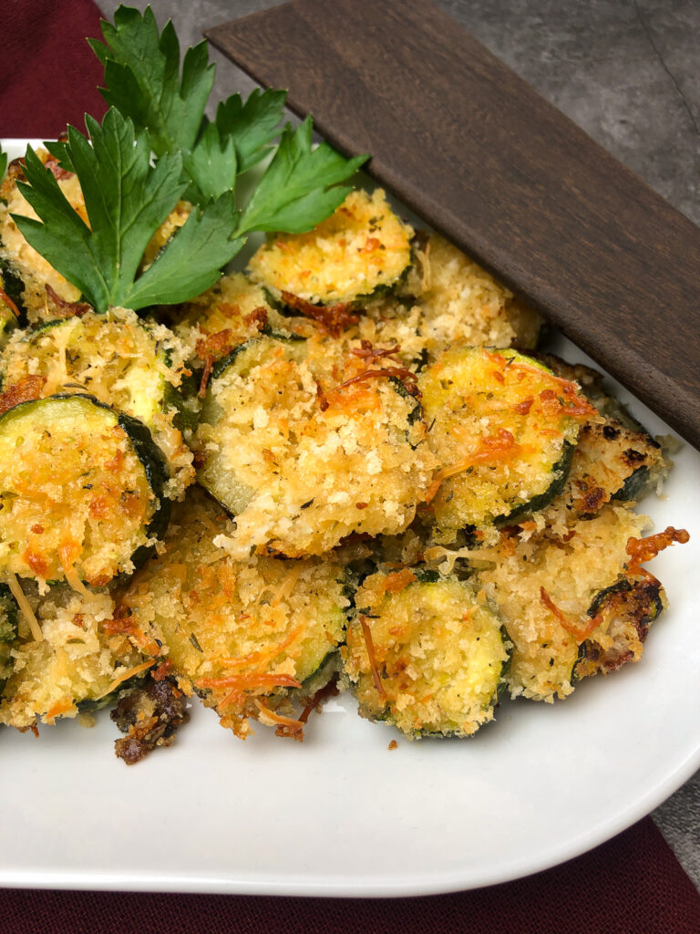 Close up image of coin-sliced, breaded zucchini that's browned and crispy.