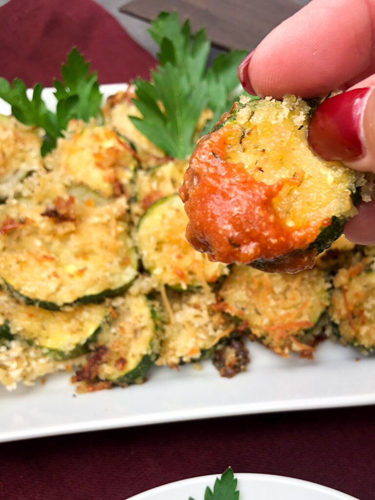 A raised zucchini chip dipped in marinara sauce.