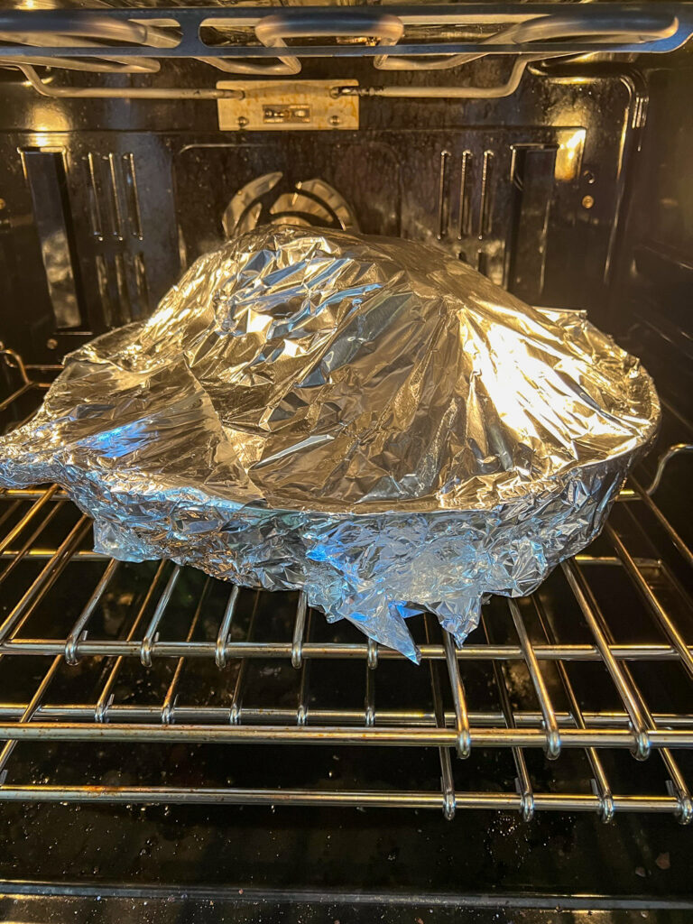 Ham and vegetables in the skillet covered with aluminum foil placed in the oven.