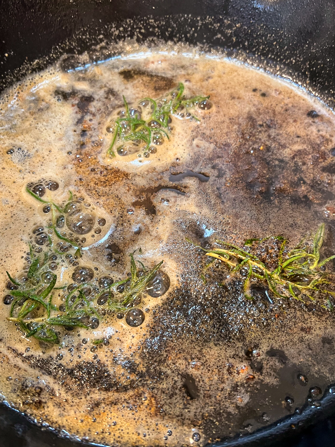 Butter, granulated garlic, and fresh rosemary in a hot skillet.