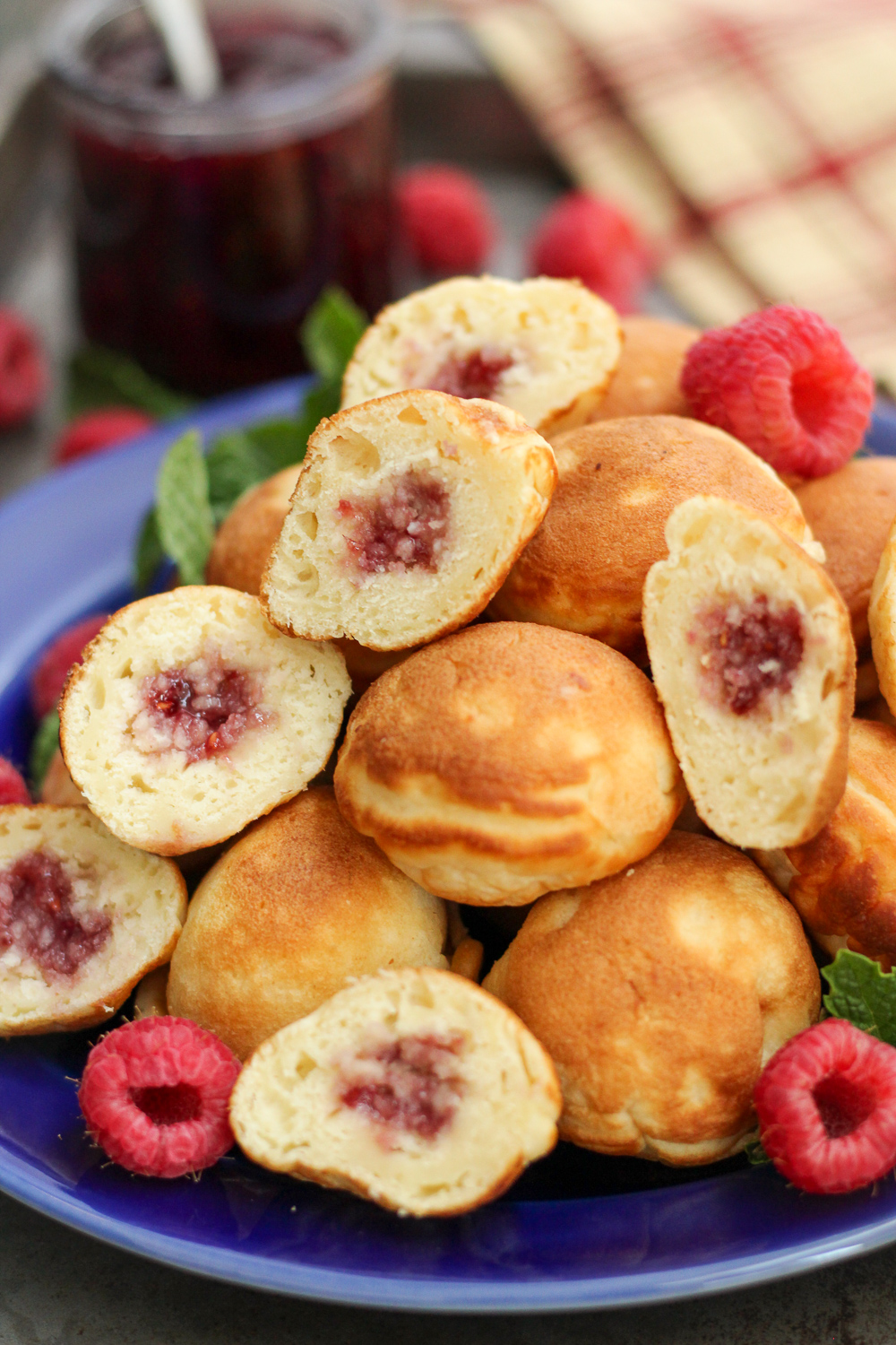 Raspberry jam filled ebelskivers or danish pancake balls on a blue plate.