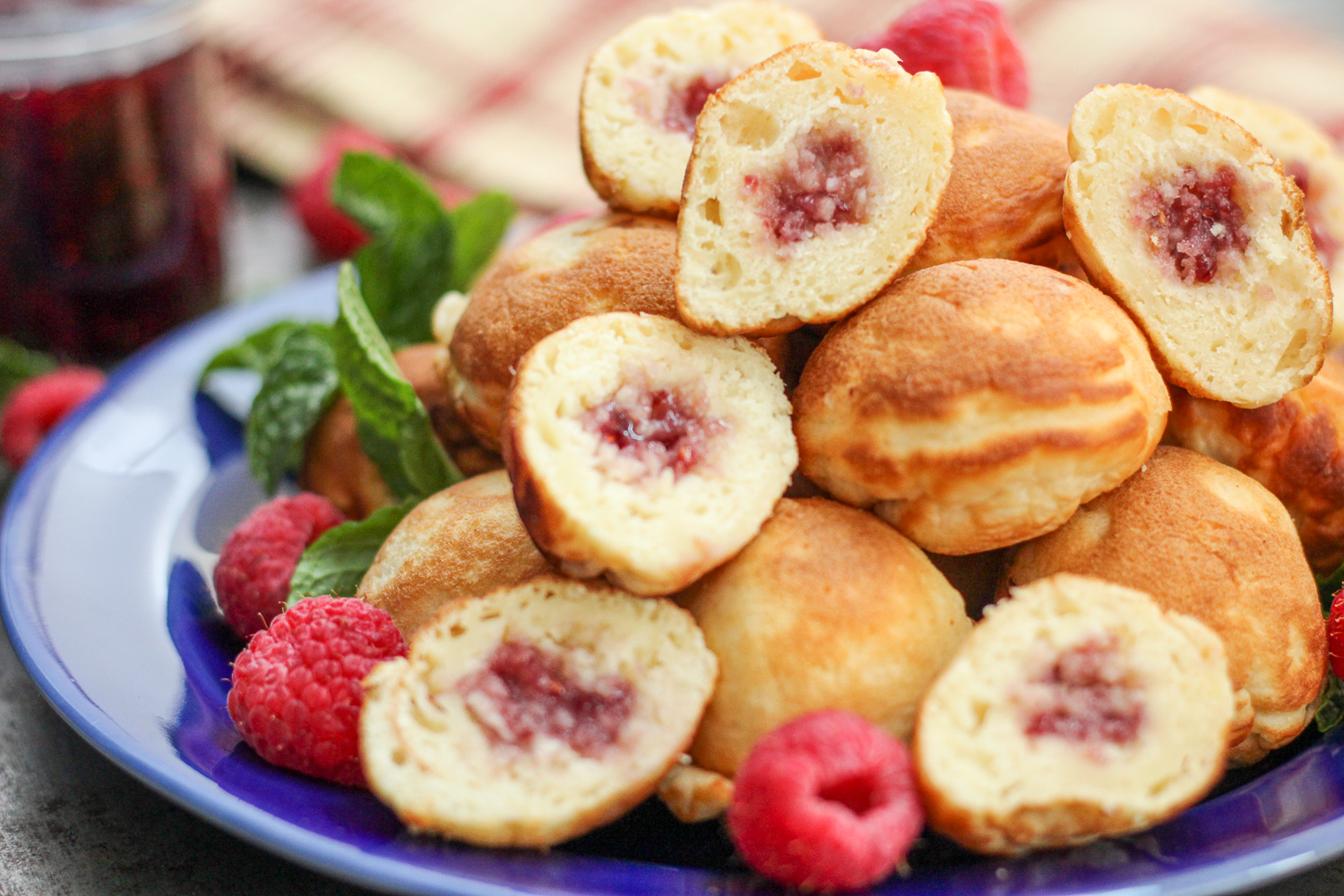 Raspberry jam filled eblesivers on a blue plate.